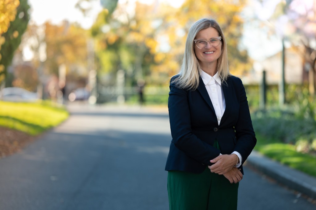 Picture of Susanne in a blazer, white shirt and green pants. She has blonde hair and glasses.